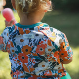 Child wearing a colorful floral shirt with a brand label outdoors