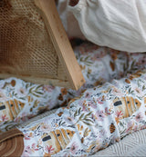 Child wearing a floral-patterned outfit interacting with a wooden beehive toy.